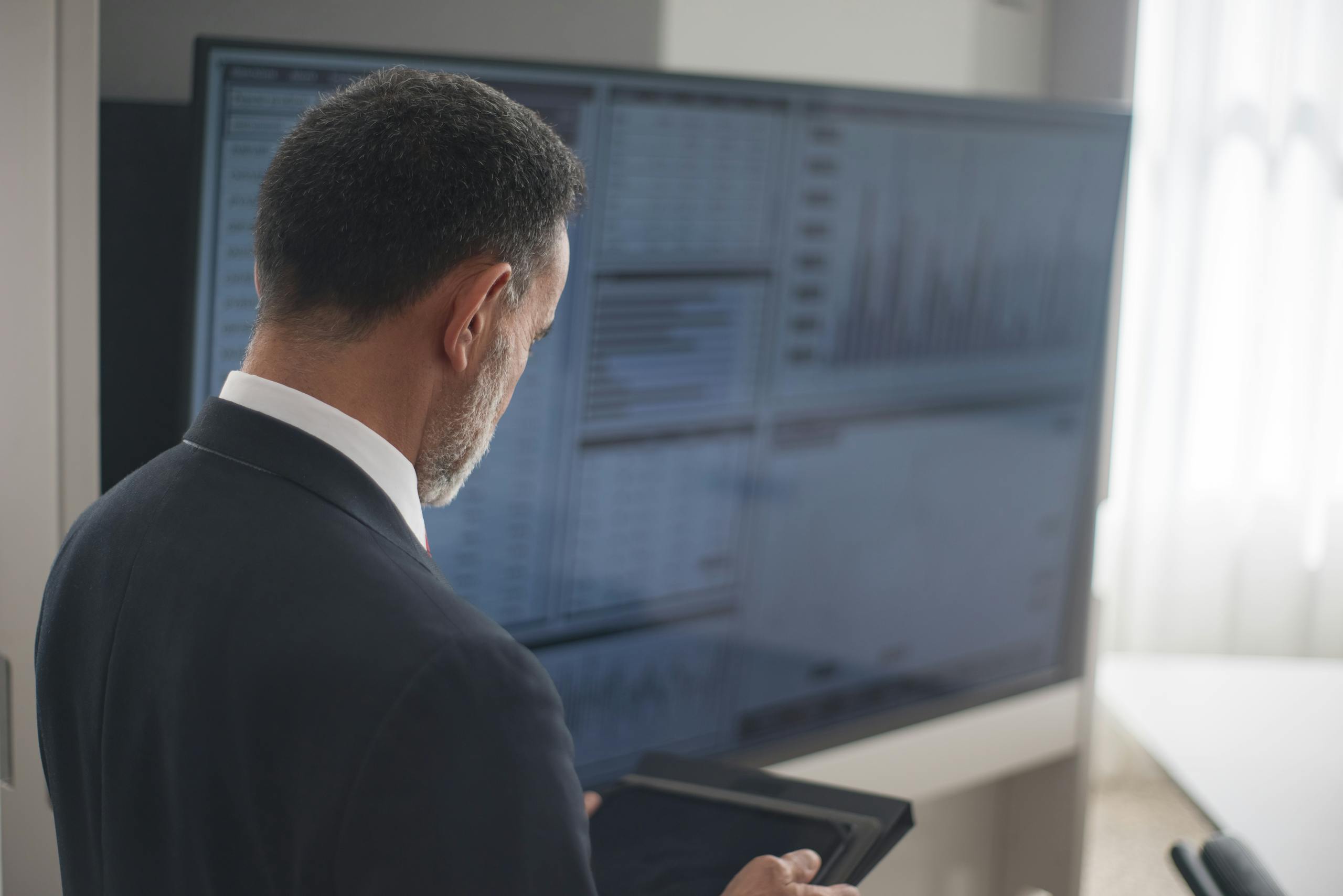 Professional analyzing stock markets on a digital tablet in a modern office setting. Investment Planner