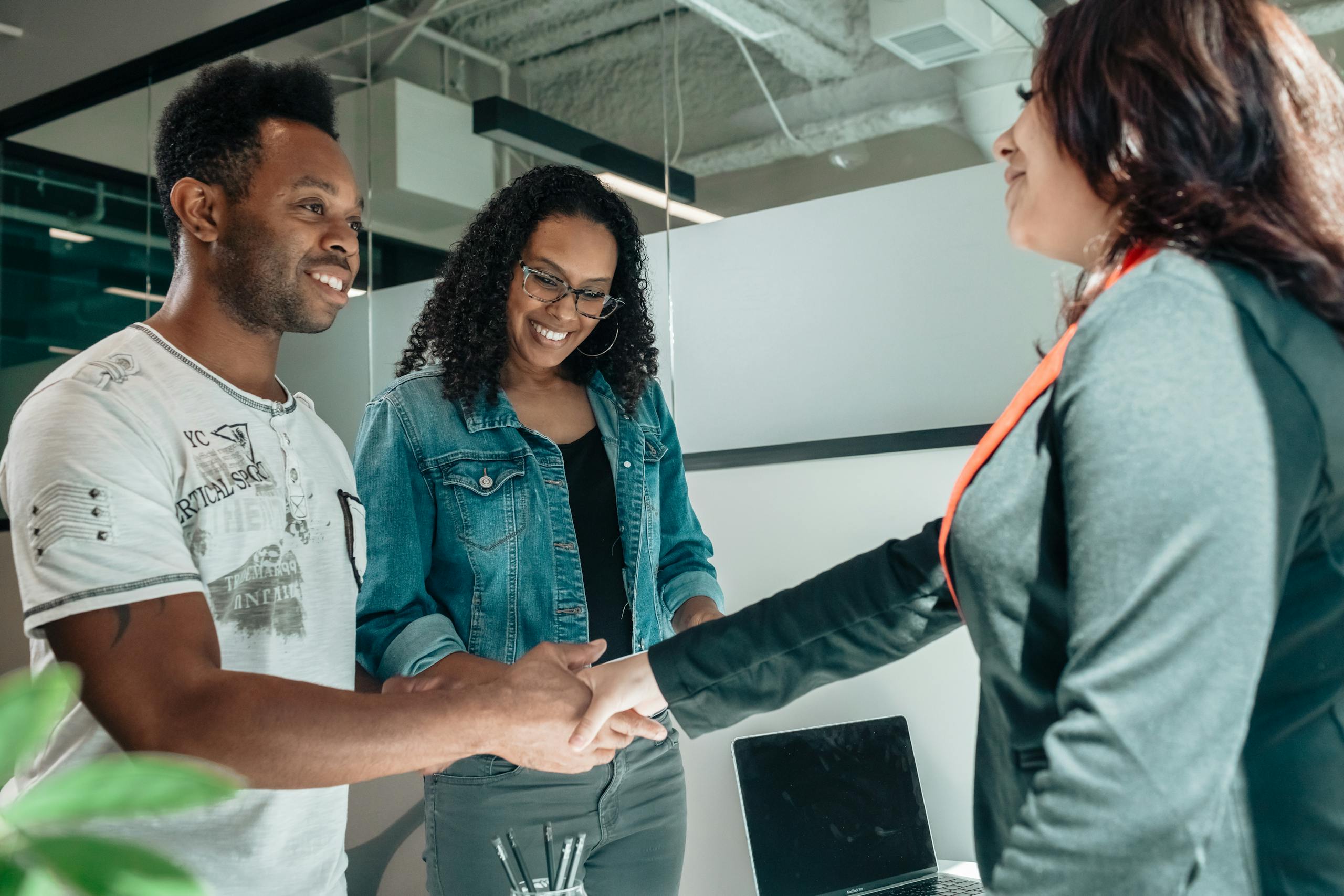 Smiling couple shaking hands with advisor in modern office. Personal Finance Management