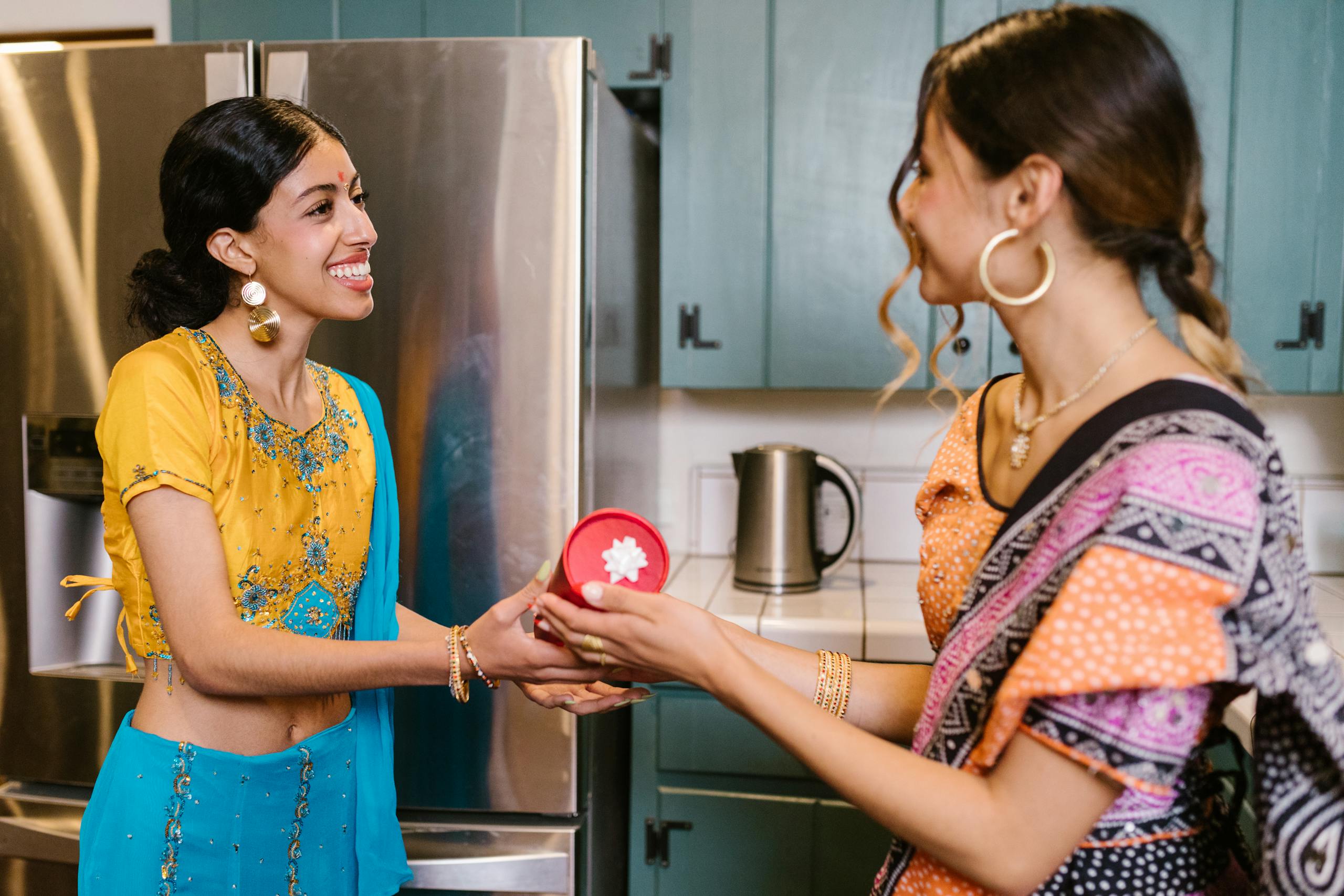 South Asian women celebrating with gifts in traditional clothing, evoking a festive spirit.