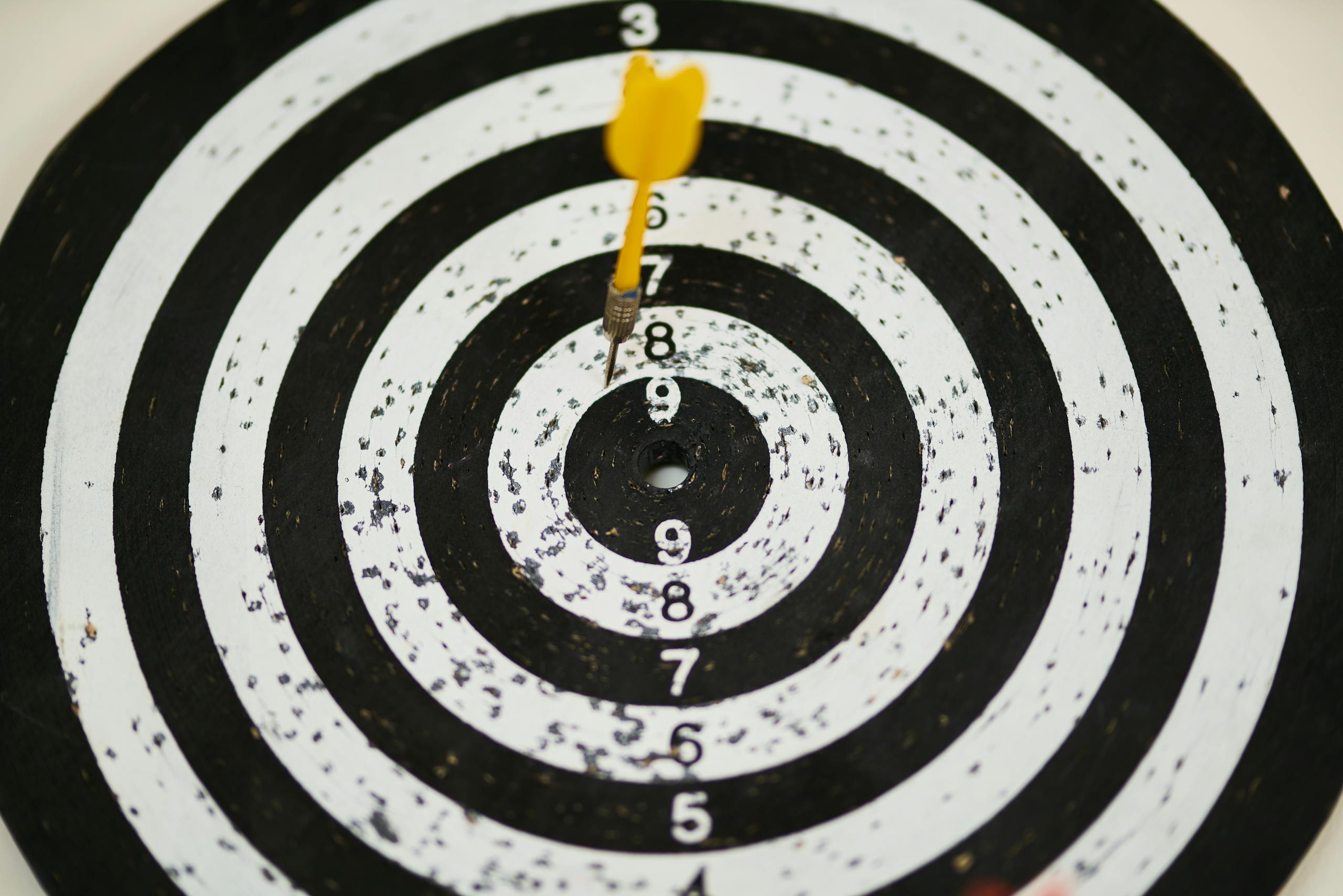 Close-up of a dart hitting the bullseye on a black and white target board symbolizing success of achieving your financial goals
